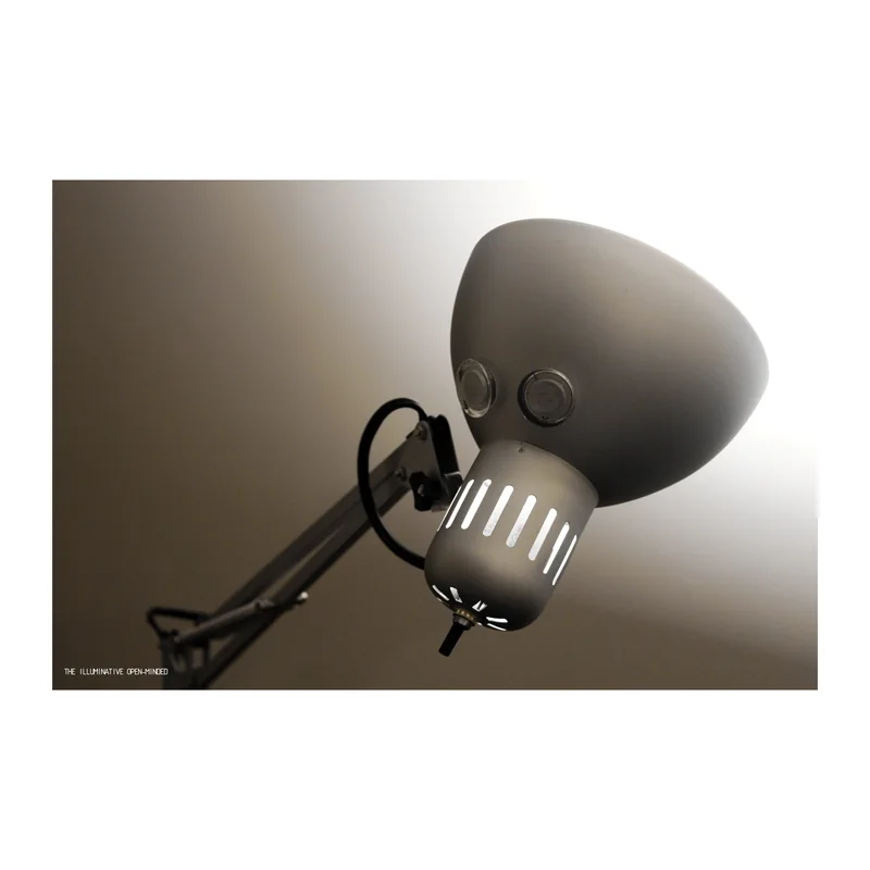 A sculptural desk lamp with a face made from circular eyes and a slotted metal mouth